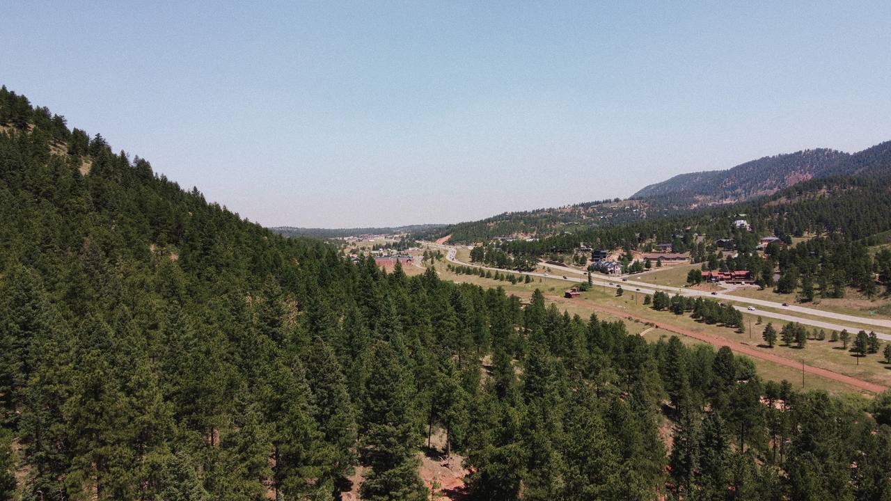 Aerial view of the quiet valley, forest, and nearby mountains around Wishing Well